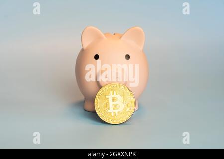 Banque de piggy avec une pièce de monnaie Bitcoin d'or nouvel argent virtuel sur un fond gris Banque D'Images