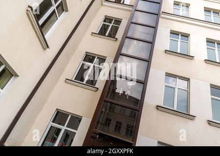 Ascenseur en verre sur une façade de maison à plusieurs étages. Un exemple de solution vivante pour les personnes ayant un handicap de marche. Banque D'Images