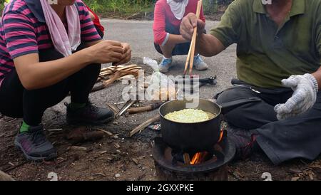 Cuisiner des hochements de tête instantanés à l'extérieur dans un pot noir au pique-nique au feu. Banque D'Images