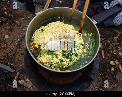 Cuisiner des hochements de tête instantanés à l'extérieur dans un pot noir au pique-nique au feu. Banque D'Images