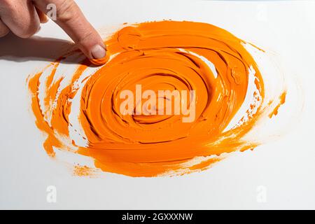 étalez une bande de couleur acrylique orange avec votre doigt Banque D'Images