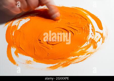 étalez une bande de couleur acrylique orange avec votre doigt Banque D'Images