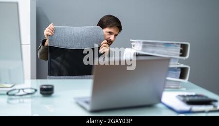 Un homme effrayé se cache derrière le bureau dans la chambre Banque D'Images