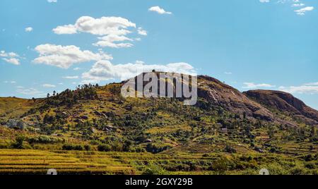 Paysage typique de Madagascar - rizières en terrasse vertes et jaunes sur de petites collines avec des maisons en argile dans la région près d'Ambositra. Banque D'Images