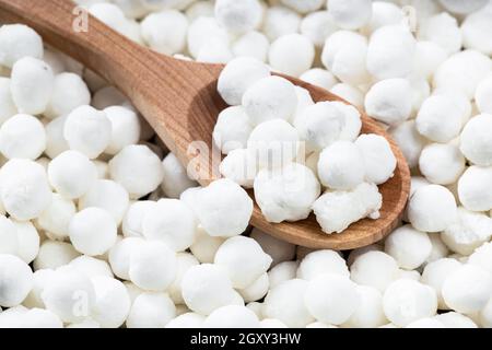 au-dessus de la vue de la cuillère en bois avec des perles de tapioca crues à proximité sur la pile de sucre Banque D'Images