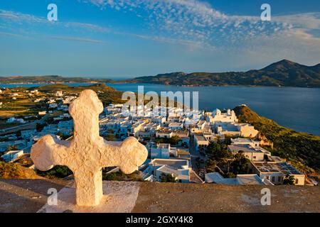 Grec orthodoxe Christianisme concept fond - Croix chrétienne avec le village de Plaka sur l'île de Milos en arrière-plan au coucher du soleil.Ville de Plaka, île de Milos, Banque D'Images