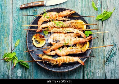 Langoustines grillées, crevettes rôties sur une brochette. Langoustines frits avec des herbes sur une table en bois Banque D'Images