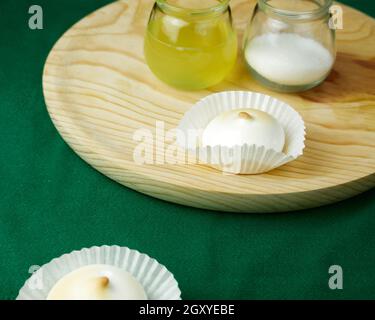 Plusieurs desserts français meringue sous forme de silicone moules sur nappe verte et ses ingrédients sur une assiette ronde en bois Banque D'Images