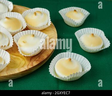 Plusieurs desserts français meringues en silicone moules sur une assiette ronde en bois et les autres sur une nappe verte Banque D'Images