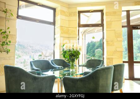 Roses blanches dans un vase sur une table et des chaises en verre.Fleurs sur le bureau dans la salle de réunion et le fauteuil Banque D'Images