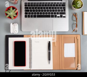 Ordinateur portable, téléphone portable et agenda ouvert sur un bureau gris vue sur le dessus. Concept d'entreprise Banque D'Images