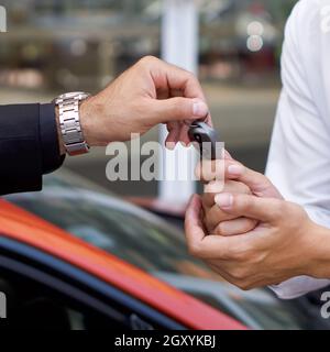 Un homme d'affaires en costume noir qui se charge de la clé de voiture pour le personnel de service de voiturier. Gros plan Banque D'Images