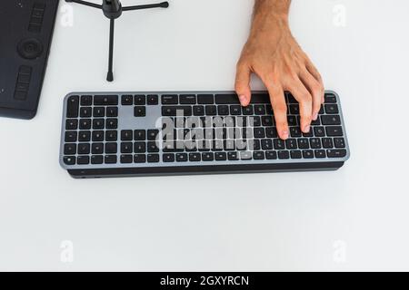 Homme anonyme travaillant sur un ordinateur à la table avec une tablette graphique Banque D'Images