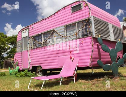 Remorque de voyage rose avec chaise et cactus avec ciel bleu et nuages Banque D'Images