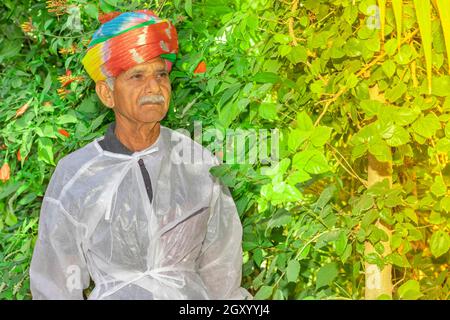 Gros plan portrait d'un agriculteur indien se tient dans le jardin avec un turban de couleur attaché sur sa tête selon la tradition hindoue Rajasthani.et effet de lumière b Banque D'Images
