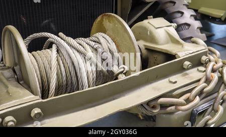 Une photo détaillée d'un treuil mécanique automobile avec câble. Une vieille corde rouillée attachée à un véhicule militaire lourd Banque D'Images