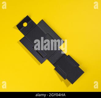 boîte de protection intérieure pliable noire en carton ondulé pour les emballages avec produits cassables sur fond jaune, pour la parfumerie Banque D'Images