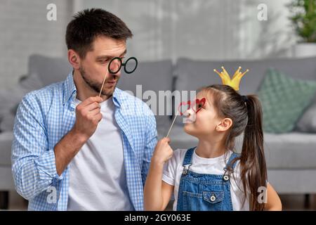 père heureux et petite fille de l'enfant tenant des verres en papier sur bâton . jour du père Banque D'Images