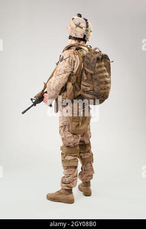 Soldat en uniforme de marine américaine avec carabine sur fond gris clair, tir en studio Banque D'Images