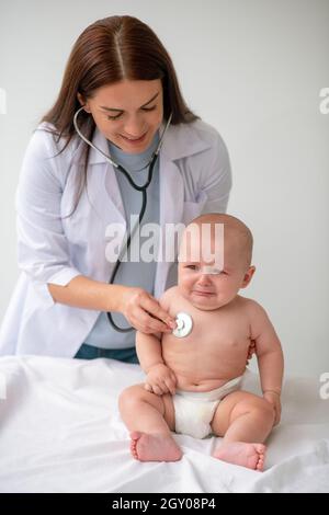 Médecin écoutant le rythme cardiaque de l'enfant avec un stéthoscope stérile Banque D'Images