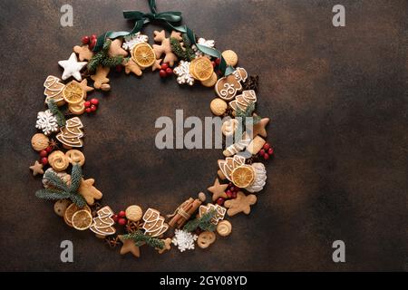 Couronne de Noël créative et douce avec assortiment de biscuits, baies sur fond marron avec espace pour les copies. Nouvelle année. Vue de dessus. Carte de vœux de Noël. Banque D'Images