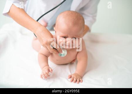 Bébé triste examiné par un médecin avec un stéthoscope Banque D'Images