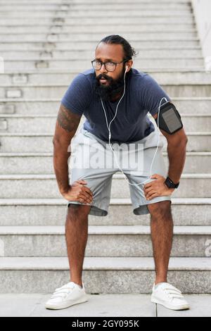 Jeune Indien épuisé, la barbe penchée sur les genoux tout en se reposant sur les escaliers Banque D'Images