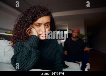 Femme de race mixte en colère contre le copain noir tout en luttant sur le canapé dans l'appartement moderne Banque D'Images