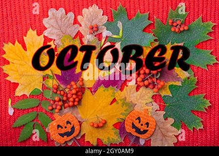 Forme de citrouille avec un sourire effrayant Jack o Lantern, réveil orange et l'inscription OCTOBRE sur un fond de feuilles séchées, baies de rowan sur un re Banque D'Images