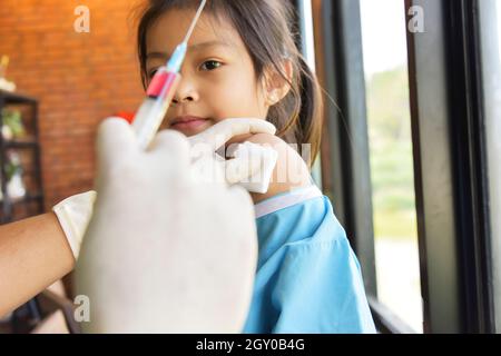 Concept de vaccination. Homme en robe chirurgicale médecin vaccinant une petite fille mignonne en clinique. Médecins pédiatres injectant le vaccin pour mignon une smilin heureuse Banque D'Images