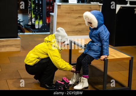 Femme aide sa fille mettre ses patins sur avant qu'elle l'emmène à une leçon de patinage. Banque D'Images