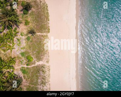Tir de drone aérien vers le bas de la plage vide de la baie de Sanya avec du sable blanc et de l'eau sur l'île tropicale de Hainan Chine Banque D'Images