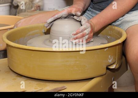 Travailler avec de l'argile dans un studio de poterie en jetant un pot sur la roue de potter Banque D'Images