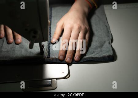 Mains d'une jeune fille dans un atelier de couture.Coudre sur une fermeture à glissière sur une machine à coudre.Concept de couture. Banque D'Images