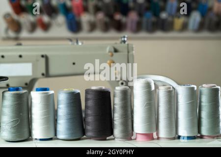 Plusieurs bobines de fil de couleur pour la couture et la broderie sur une table en bois blanc. Banque D'Images