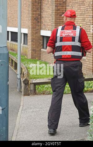 Rugby Town Ranger dans un centre-ville en uniforme rouge destiné aux activités criminelles, avec des liaisons radio directes avec des opérateurs de vidéosurveillance et la police Warwickshire UK Banque D'Images