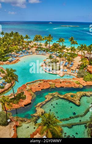 Vue depuis le balcon du complexe avec piscine à rayons, piscine, palmiers et océan Banque D'Images