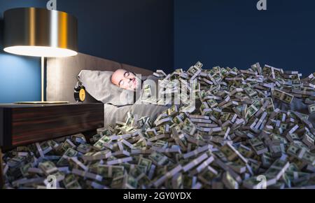 Homme souriant dormant dans un lit couvert de dollars d'argent. Concept de richesse. Banque D'Images