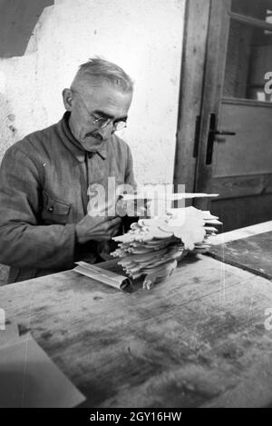 Ein Mitarbeiter in den Heller Kunst Werkstätten in der Eifel schleift ausgesägten Holzfiguren die Kanten der ab, Deutschland 1930 er Jahre. Un employé de la Heller Kunst des ateliers dans l'Eifel le meulage des bords de l'out figures en bois scié, Allemagne 1930. Banque D'Images