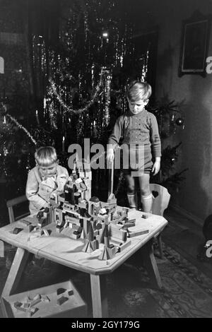 Zwei Jungen spielen am Weihnachtsabend mit den neuen Bauklötzen, Deutschland 1938. Deux garçons jouant avec la nouvelle série de blocs de jouets sous l'arbre de Noël, de l'Allemagne 1930 Banque D'Images