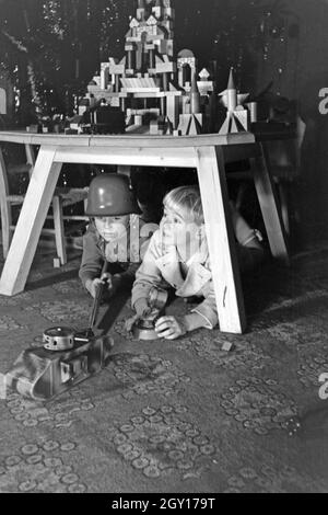 Zwei Jungen spielen am Weihnachtsabend mit Stahlhelm Gewehr und Soldaten Deutschland, 1938. Deux garçons soldats jouant avec un casque d'acier et un fusil jouet sous l'arbre de Noël, de l'Allemagne 1930 Banque D'Images