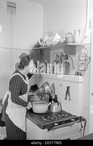 Eine Frau steht am herd in der Küche und kocht, Deutschland 1930 er Jahre. Une femme debout dans la cuisine sur la cuisson au four, l'Allemagne des années 1930. Banque D'Images