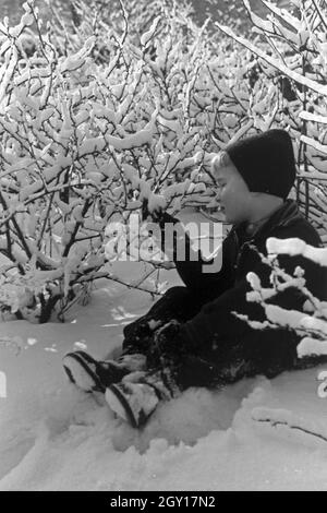 Ein kleiner Junge sitzt im Schnee, Deutschland 1930er Jahre. Un petit garçon assis dans la neige, l'Allemagne des années 1930. Banque D'Images