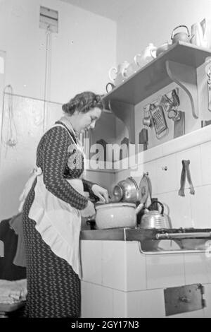 Eine Frau steht am herd in der Küche und kocht, Deutschland 1930 er Jahre. Une femme debout dans la cuisine sur la cuisson au four, l'Allemagne des années 1930. Banque D'Images