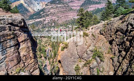 Vue aérienne du canyon profond dans les montagnes avec vue sur la rivière et pont de marche traversant Banque D'Images