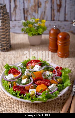 Salade chaude avec potiron, fromage feta, tomates séchées, olives, arugula et oignon rouge. Gros plan. Banque D'Images