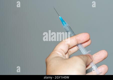 main de l'homme tenant la seringue de vaccination, pointant vers le haut, seringue prête à l'emploi. instruments de vaccination (covid-19, grippe) pandémie et santé conc Banque D'Images
