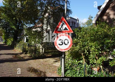 Vieux panneaux routiers dans une rue d'un village hollandais.Panneau d'avertissement de travail en cours.Limite de vitesse du panneau d'interdiction de 30 km/h.Automne, octobre, pays-Bas Banque D'Images