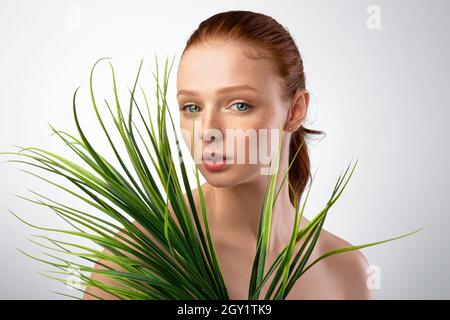 Photo de la jeune dame posant avec Green Plant dans Studio Banque D'Images