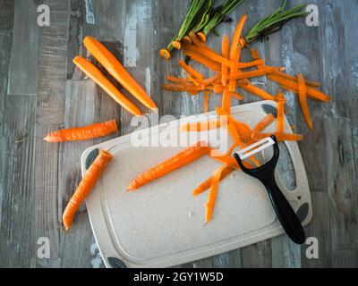 Carottes pelées couchées sur la table, à côté d'un couteau pour éplucher les légumes et les fruits, photo d'en haut, concept alimentaire Banque D'Images